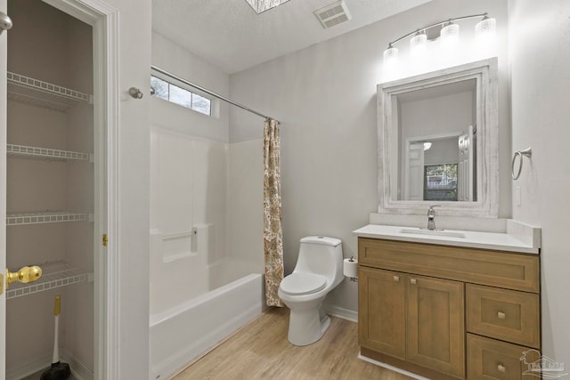 full bathroom with hardwood / wood-style floors, vanity, shower / bath combo, toilet, and a textured ceiling