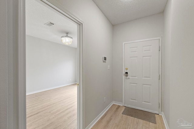 doorway featuring a textured ceiling and light wood-type flooring