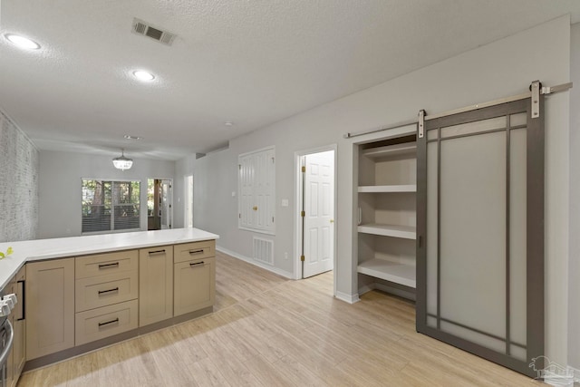 kitchen with a textured ceiling, a barn door, and light hardwood / wood-style flooring