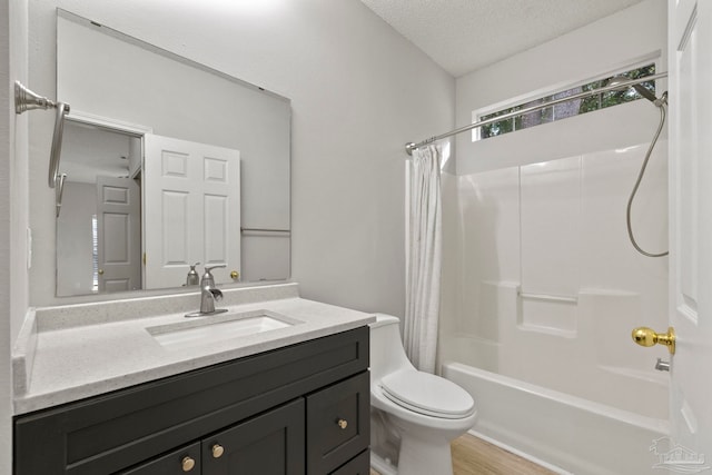 full bathroom with shower / bath combo, hardwood / wood-style floors, a textured ceiling, toilet, and vanity