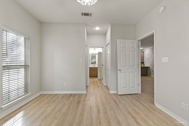 spare room featuring light hardwood / wood-style floors and a textured ceiling