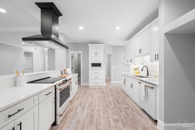 kitchen with light hardwood / wood-style floors, wall chimney range hood, sink, white cabinets, and white appliances