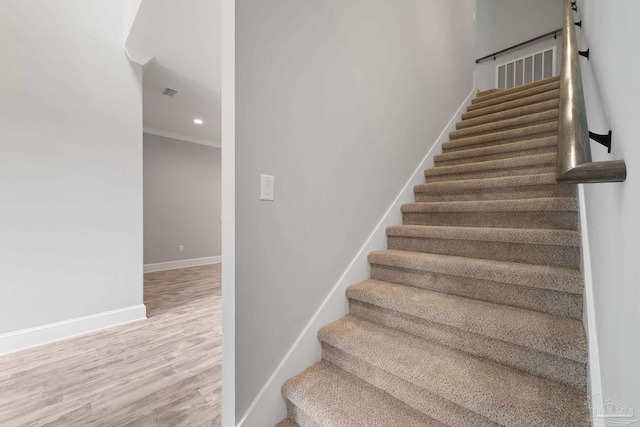 stairs with wood-type flooring, ornamental molding, and a barn door