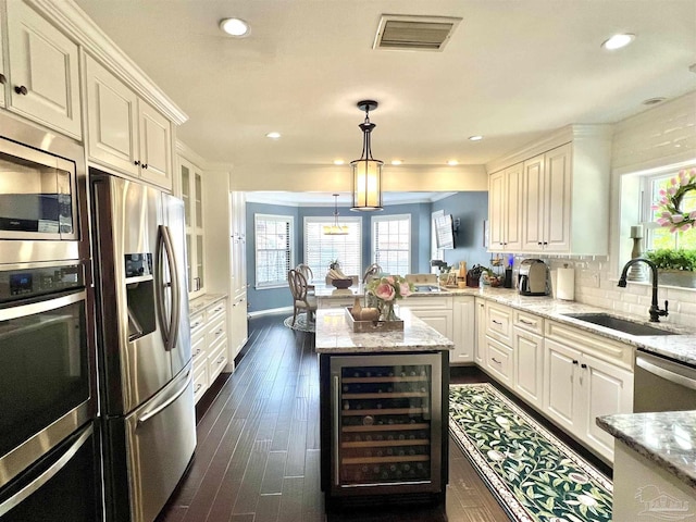 39 Blithewood Dr, Pensacola, FL 32514 - kitchen with beverage cooler, stainless steel appliances, a sink, a peninsula, and light stone counters