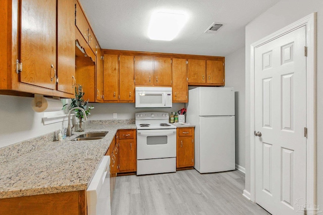6257 Mohawk Trl, Milton, FL 32583 - kitchen featuring white appliances, brown cabinetry, light wood-type flooring, and a sink