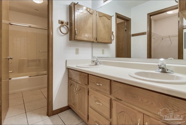 full bath featuring double vanity, shower / bath combination with glass door, a sink, and tile patterned floors