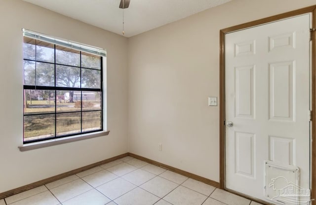 spare room featuring ceiling fan, light tile patterned flooring, and baseboards