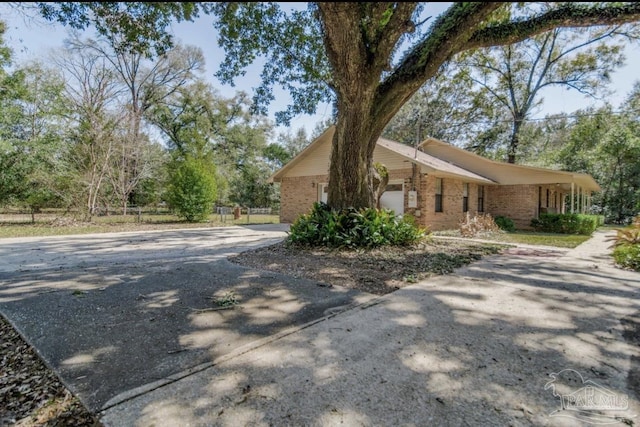 view of side of home with a garage, brick siding, and driveway