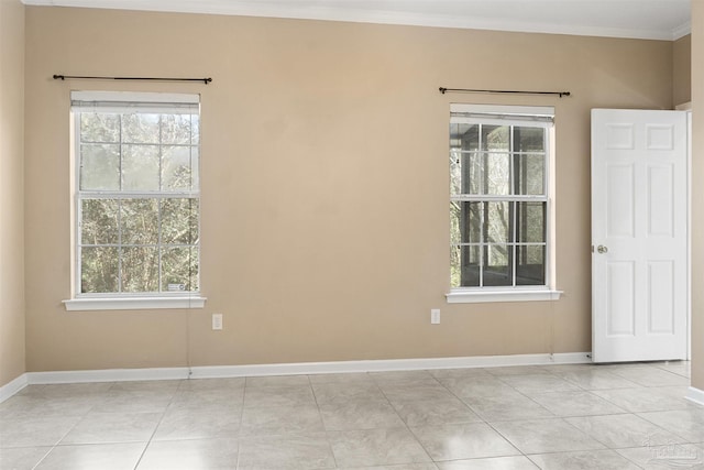 empty room featuring ornamental molding, light tile patterned flooring, plenty of natural light, and baseboards