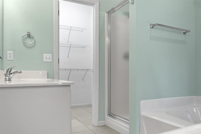 bathroom featuring tile patterned flooring, vanity, a spacious closet, a shower stall, and a bath