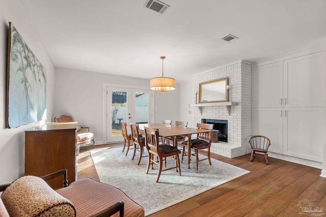 dining room featuring hardwood / wood-style floors, french doors, and a fireplace