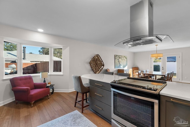 kitchen featuring plenty of natural light, pendant lighting, island range hood, and stainless steel range with electric stovetop