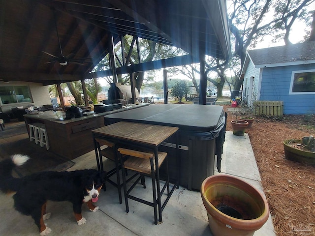 view of patio / terrace with a hot tub, a gazebo, ceiling fan, and a bar