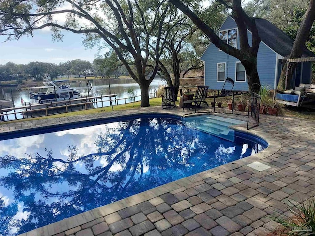 view of pool with a water view, a dock, and a patio