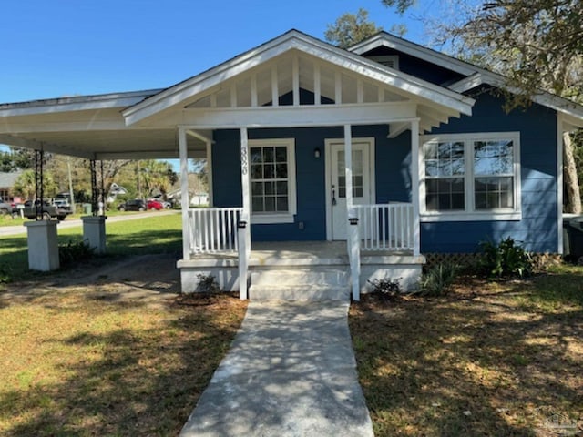 view of front of property featuring covered porch, a carport, and a front lawn