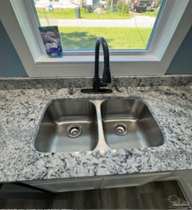 interior details featuring wood-type flooring, light stone countertops, and sink