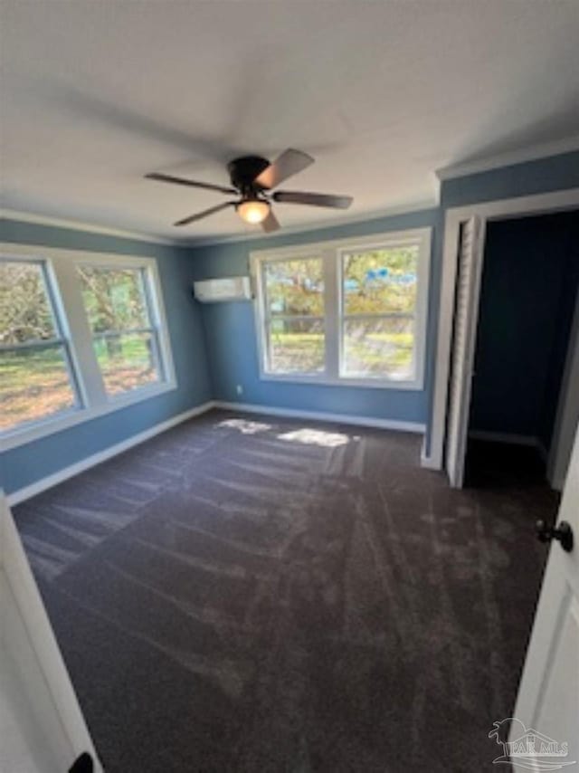 interior space featuring ceiling fan, an AC wall unit, crown molding, and dark carpet