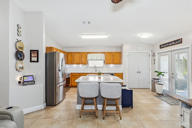 kitchen featuring backsplash, french doors, sink, appliances with stainless steel finishes, and a kitchen island