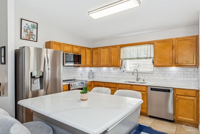 kitchen featuring appliances with stainless steel finishes, a kitchen breakfast bar, vaulted ceiling, sink, and a center island