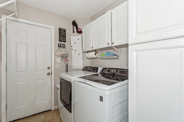 laundry room featuring washer and clothes dryer, light tile patterned floors, cabinets, and a textured ceiling