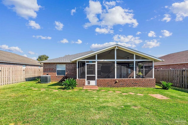 rear view of property with a sunroom, central AC unit, and a lawn