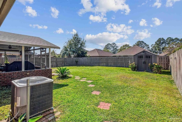 view of yard featuring central AC, a sunroom, and a storage unit