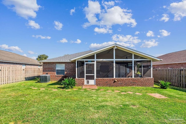 rear view of house featuring a yard, cooling unit, and a sunroom