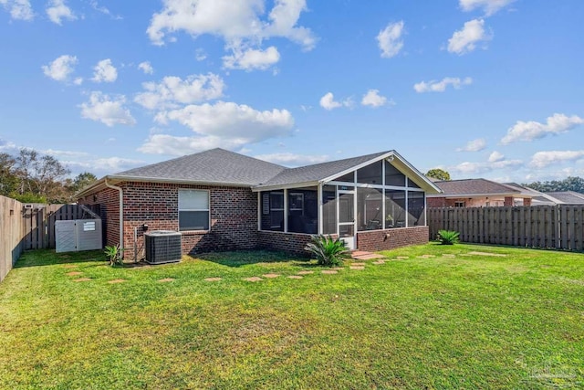 back of property with central AC, a lawn, a storage shed, and a sunroom