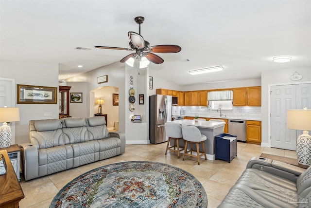 living room featuring ceiling fan, lofted ceiling, sink, and light tile patterned floors