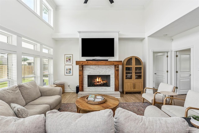 4121 Castle Gate Dr, Pace, FL 32571 - living room with a high ceiling, a stone fireplace, a ceiling fan, light wood finished floors, and ornamental molding