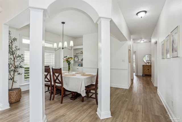 4121 Castle Gate Dr, Pace, FL 32571 - dining area featuring decorative columns, light wood-style flooring, baseboards, and a chandelier