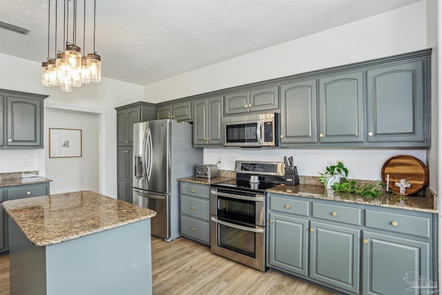 4121 Castle Gate Dr, Pace, FL 32571 - kitchen featuring stainless steel appliances, light wood-style flooring, a textured ceiling, a chandelier, and a center island