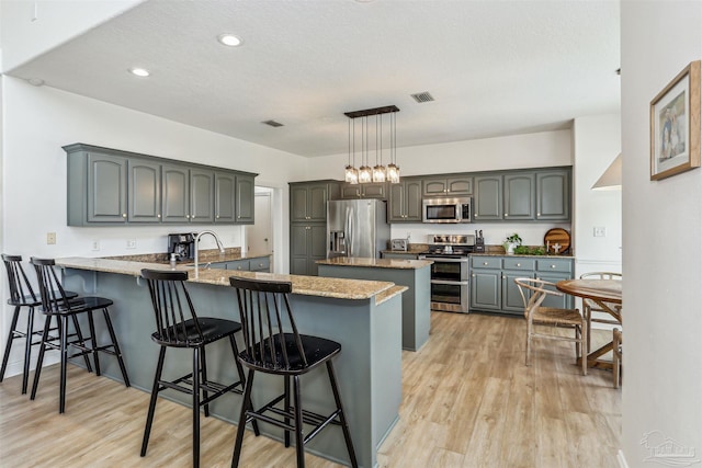 4121 Castle Gate Dr, Pace, FL 32571 - kitchen featuring appliances with stainless steel finishes, a peninsula, light wood-type flooring, a kitchen bar, and recessed lighting