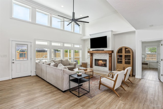 4121 Castle Gate Dr, Pace, FL 32571 - living area featuring a ceiling fan, light wood finished floors, a stone fireplace, baseboards, and a high ceiling