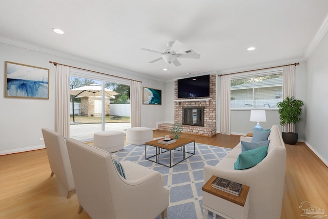 living room with ceiling fan, light hardwood / wood-style floors, crown molding, and a fireplace