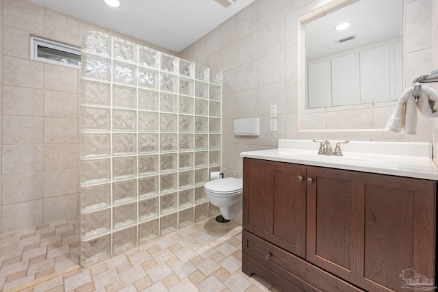 bathroom featuring tile walls, vanity, toilet, and a shower