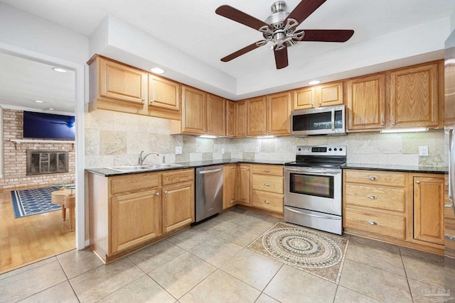 kitchen featuring a fireplace, sink, backsplash, light tile patterned floors, and appliances with stainless steel finishes