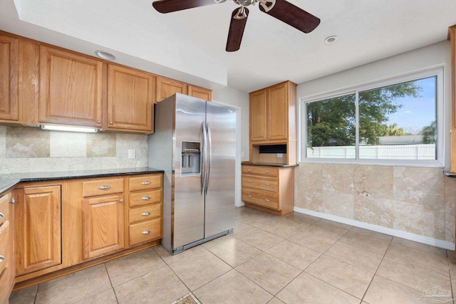 kitchen with dark stone counters, tasteful backsplash, light tile patterned flooring, and stainless steel refrigerator with ice dispenser