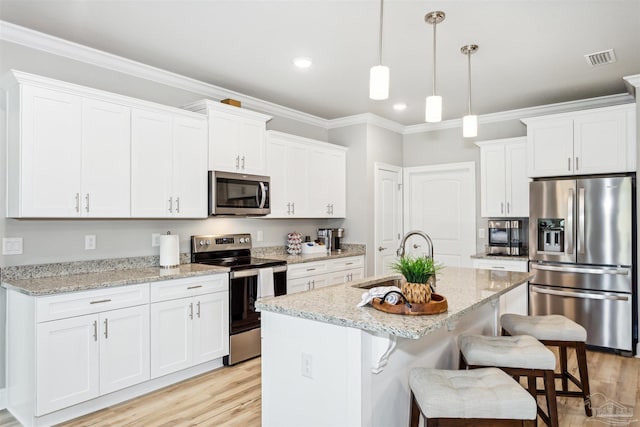 kitchen with a center island with sink, sink, light stone counters, white cabinetry, and stainless steel appliances