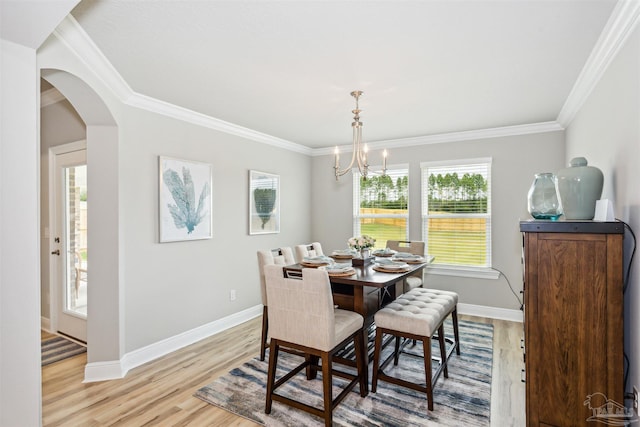 dining area featuring crown molding, an inviting chandelier, and light wood-type flooring