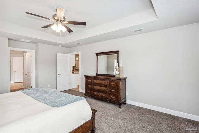 carpeted bedroom featuring ceiling fan and a raised ceiling