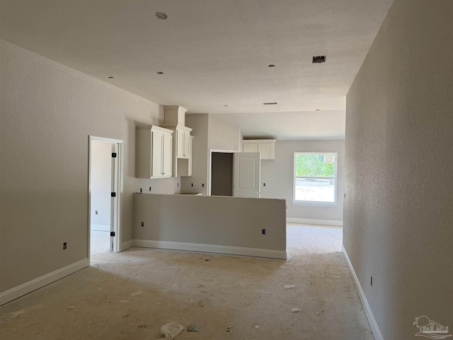spare room featuring a textured wall and baseboards