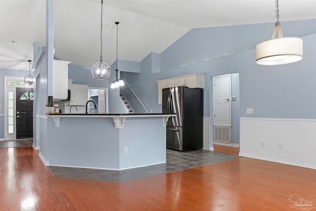 kitchen with white cabinets, pendant lighting, dark hardwood / wood-style flooring, and stainless steel refrigerator