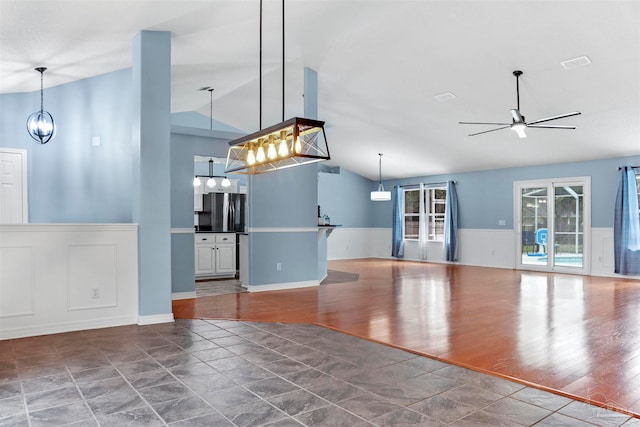 unfurnished living room with ceiling fan with notable chandelier, dark hardwood / wood-style floors, and lofted ceiling