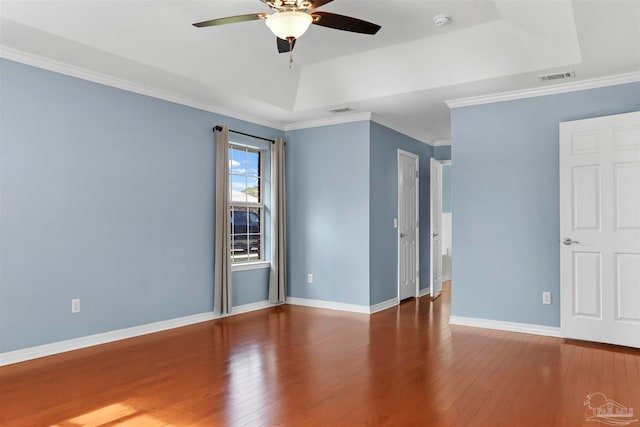 spare room featuring wood-type flooring, a tray ceiling, ceiling fan, and crown molding