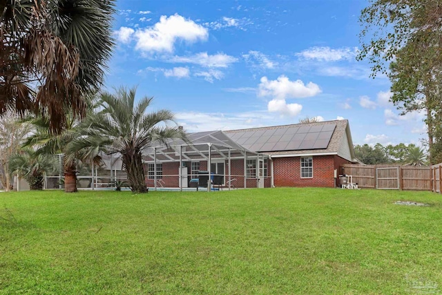 back of property with a lanai, a lawn, and solar panels