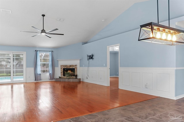 unfurnished living room with a fireplace, dark wood-type flooring, ceiling fan, and lofted ceiling