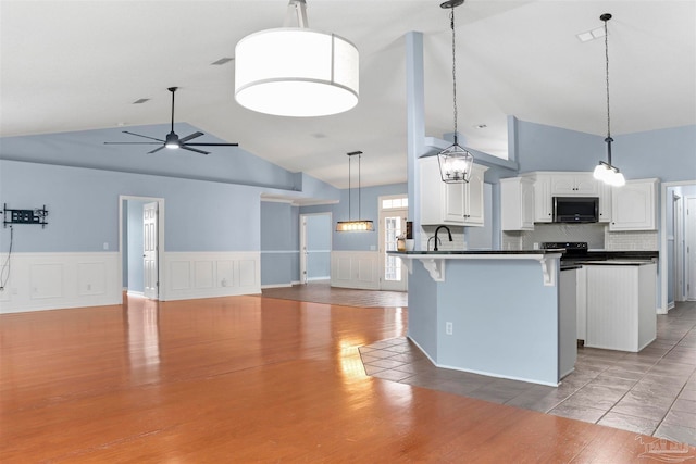 kitchen with ceiling fan, white cabinets, dark hardwood / wood-style floors, hanging light fixtures, and lofted ceiling