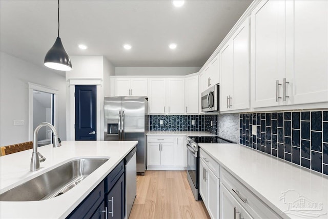 kitchen featuring appliances with stainless steel finishes, white cabinets, sink, backsplash, and light hardwood / wood-style floors