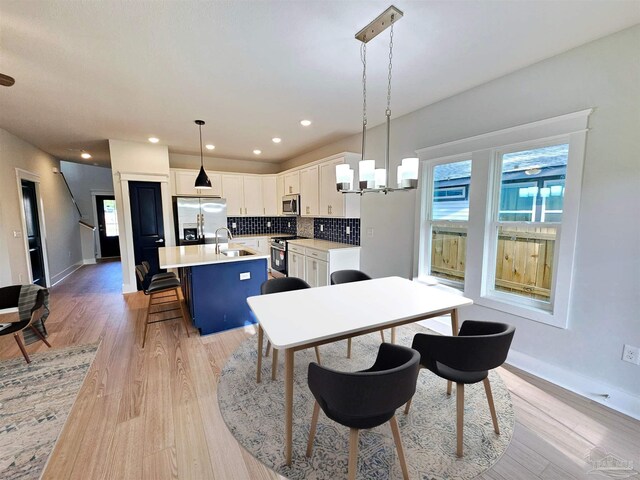 kitchen featuring ceiling fan, white cabinets, appliances with stainless steel finishes, light hardwood / wood-style flooring, and backsplash